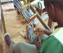 Initial stretching of the warp onto the loom. Seth is evenly dividing the ends of the warp in anticipation of rolling it onto the apron bar.